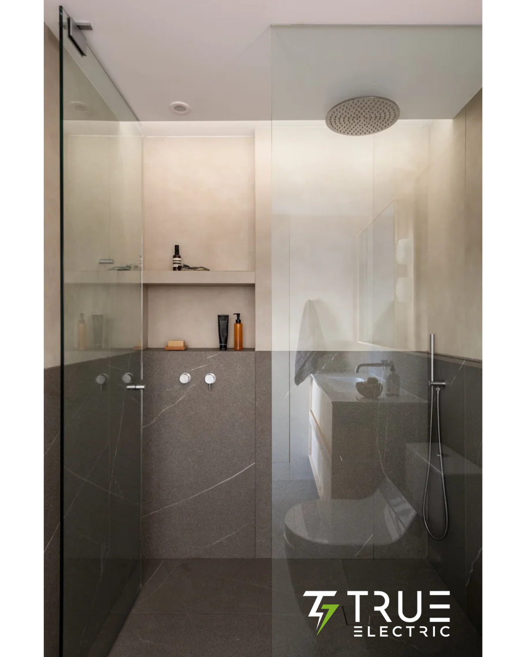 Recessed architectural LED strip lighting illuminating dark marble tile in a luxury walk-in shower.