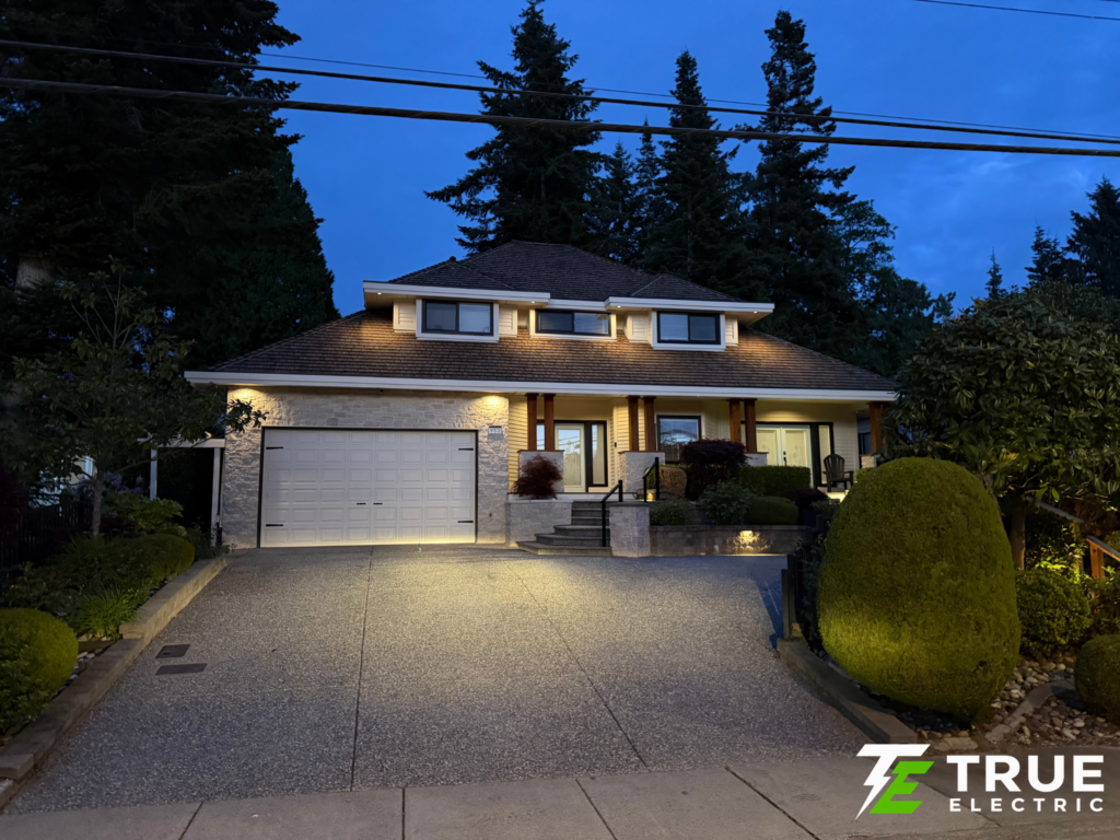 Modern house in the King George Corridor of South Surrey illuminated at night by custom exterior soffit lighting.