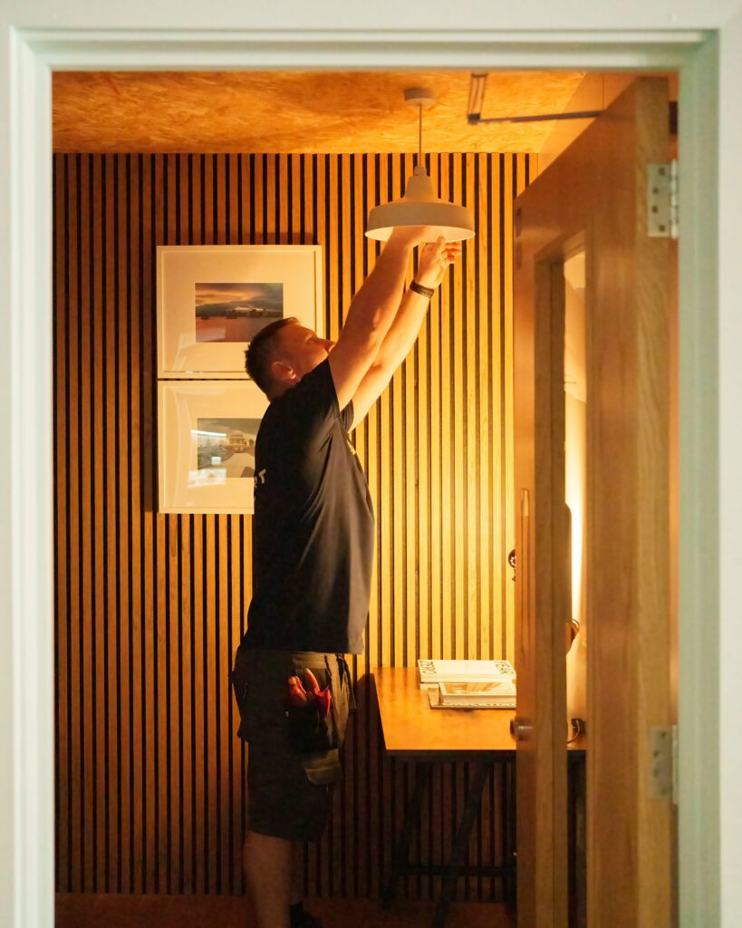 A residential electrician near me testing a faulty living room wall outlet during a fast home service call.