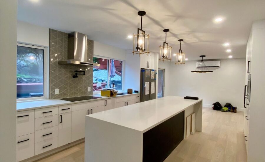 Under-cabinet LED strip lighting illuminating a white quartz countertop in a modern bright kitchen remodel.