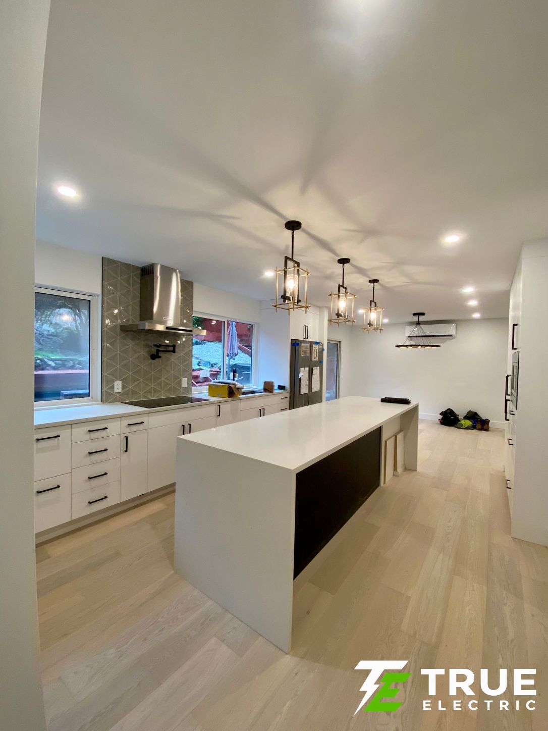 Under-cabinet LED strip lighting illuminating a white quartz countertop in a modern bright kitchen remodel.
